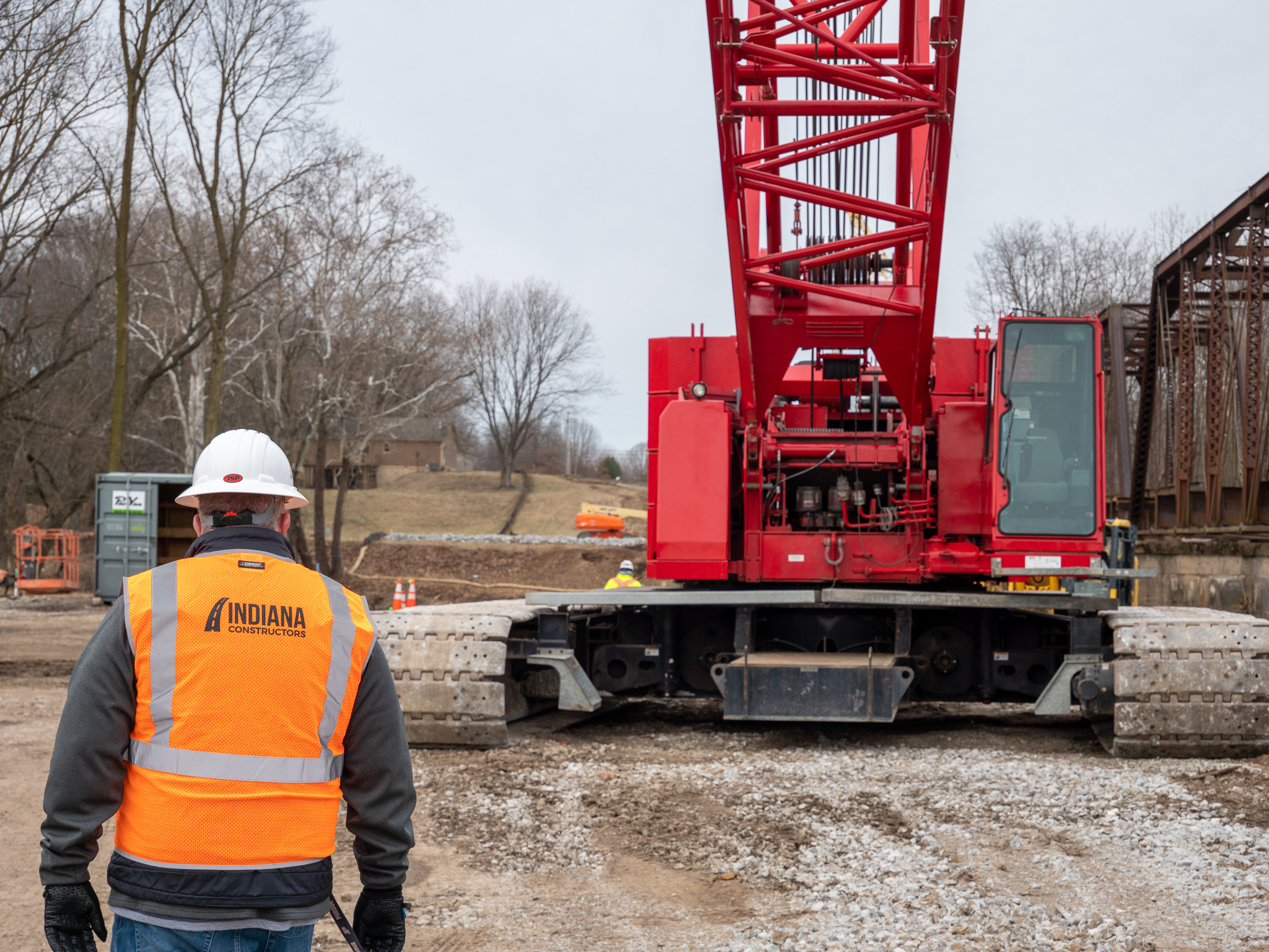 Work IN Roads team member Eric Fisher stands next to large red crane at jobsite